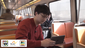 A TravelMate participant sits on the metro train holding an iPad.
