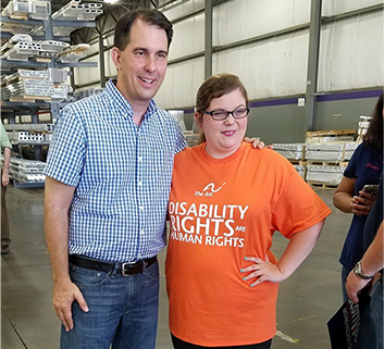 An advocate wearing a "disability rights are human rights" t shirt poses with past Wisconsin governor Scott Walker
