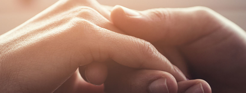 Close up of two hands gently clasping each other