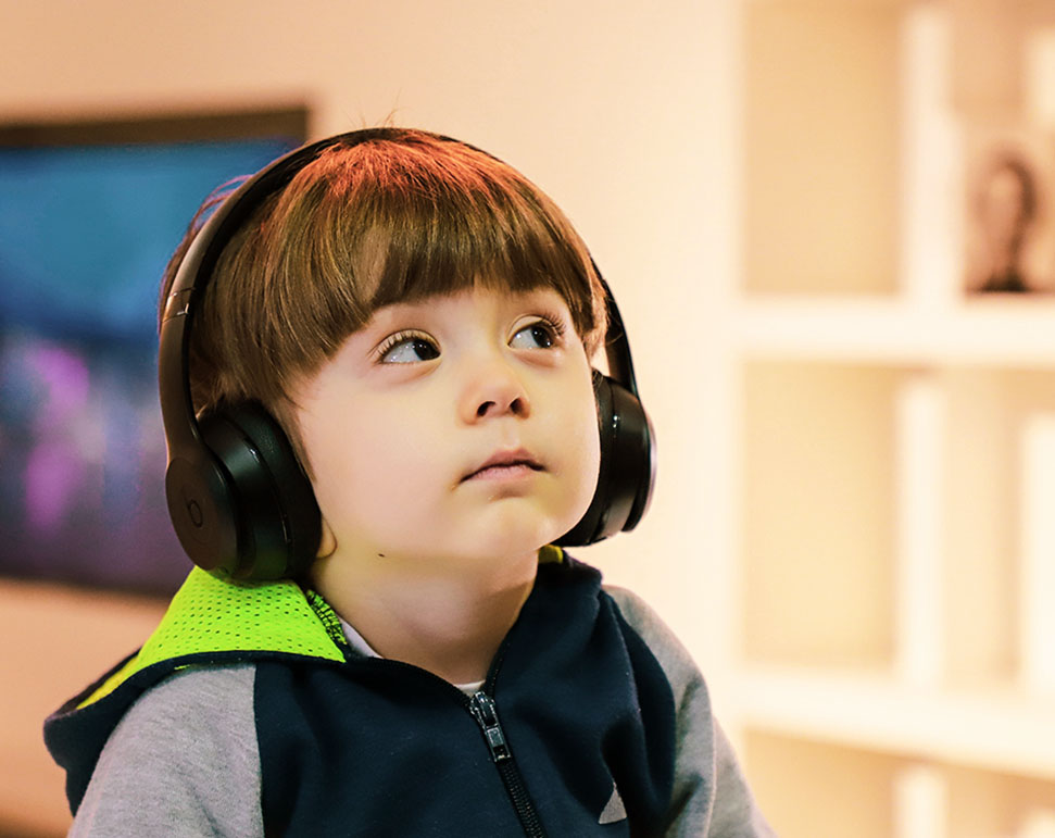 Young boy wears headphones and looks up