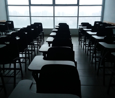 Photo of desks in a classroom with dim, moody lighting