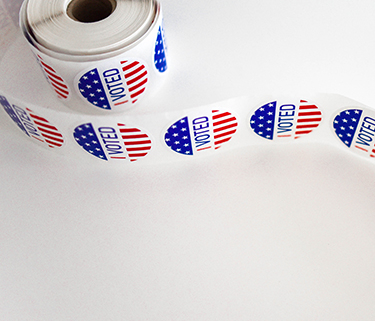 Roll of red, white, and blue "I voted" stickers on a white table