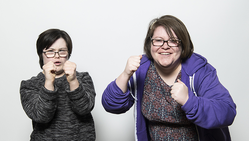 Two woman with clenched fists smile and pretend to box