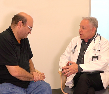 two men, a patient and a doctor, seated and talking