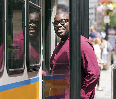 Man in red shirt getting on the bus and smiling at camera