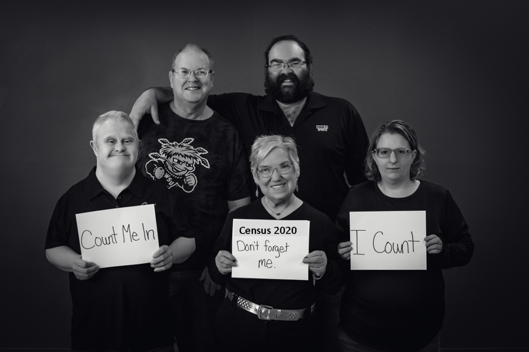 Black and white photo of people holding signs that say "I Count. Count me in. Census 2020"