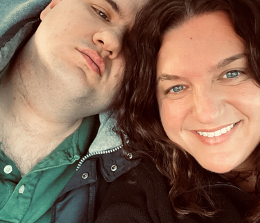A woman and her brother take a selfie in a car. The woman is smiling and the man has his eyes closed and a neutral expression.