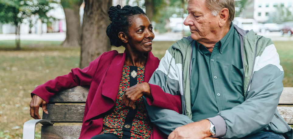 Woman and man sit together on a park bench. Home and community-based services make life in the community possible.
