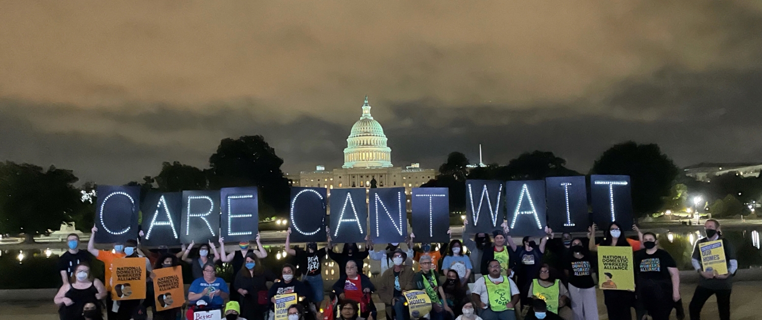 A group of activitists poses in front of the US Capitol at night, holding light up signs that say Care Can't Wait