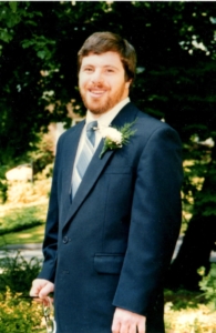 A man in a suit, smiling at the camera. 
