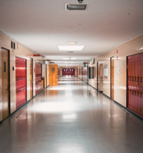 A long school hallway with red lockers and classroom doors lining either side