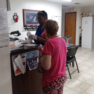 Betty Davis stands in a kitchen with a client, assisting her client with medications.