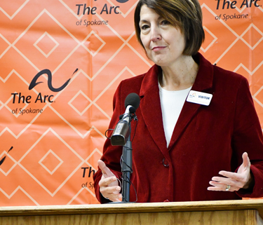 Congresswoman Cathy McMorris Rodgers, U.S. Representative for Washington State stands in front of a podium. Behind her is an orange sign with The Arc of Spokane logo.