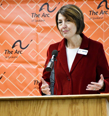 Congresswoman Cathy McMorris Rodgers, U.S. Representative for Washington State stands in front of a podium. Behind her is an orange sign with The Arc of Spokane logo.