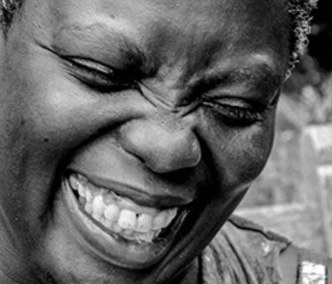 A black and white photo of Lois Curtis, a Black woman with disabilities. The image is up close of just her face, smiling broadly.
